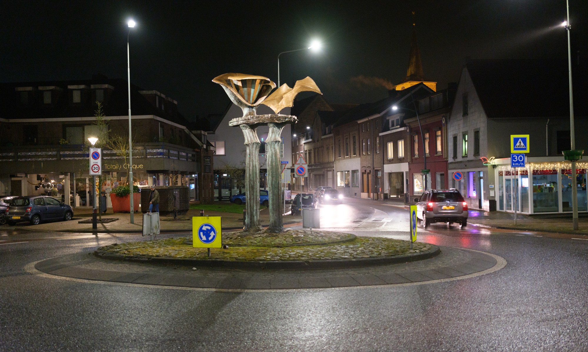 Roundabout fully illuminated in the Evening. Scupture in the Middle.