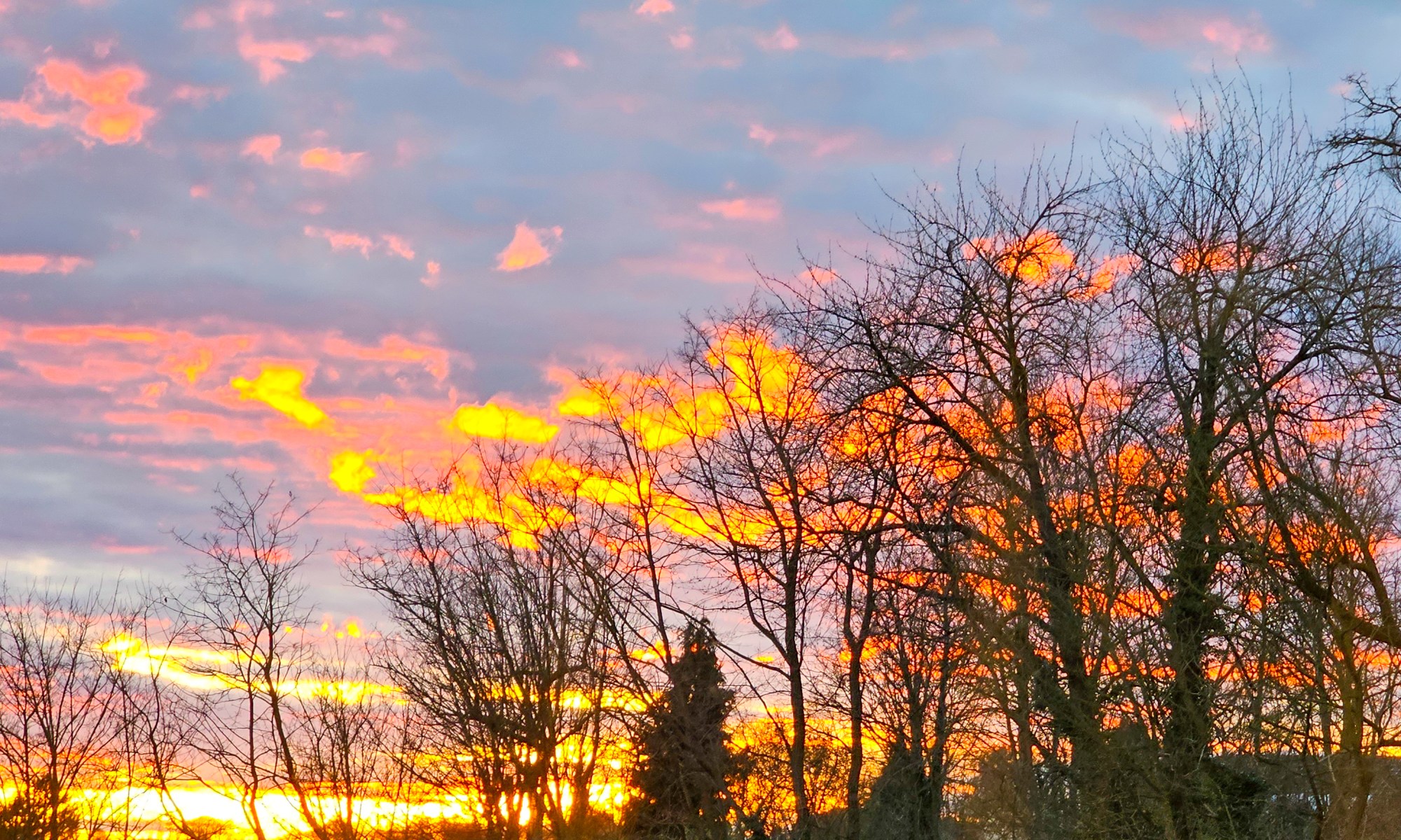 Sun now behind the Horizon while illuminating Clouds in Gold, Yellow and Red
